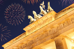 The famous Bradenburg Gate lit up on New Years Eve with fireworks booming in the night sky.