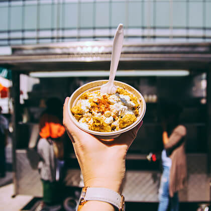 A Topdeck tourist holding up a cup of street food in Manhattan.