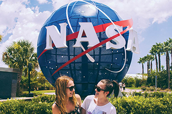 Couple posing in front of NASA globe monument in Florida.