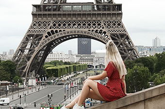 Lady sitting on wall looking over Eiffel Tower.