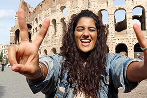 A Topdeck traveler posing in front of the Colosseum of Rome holding up Peace Signs.