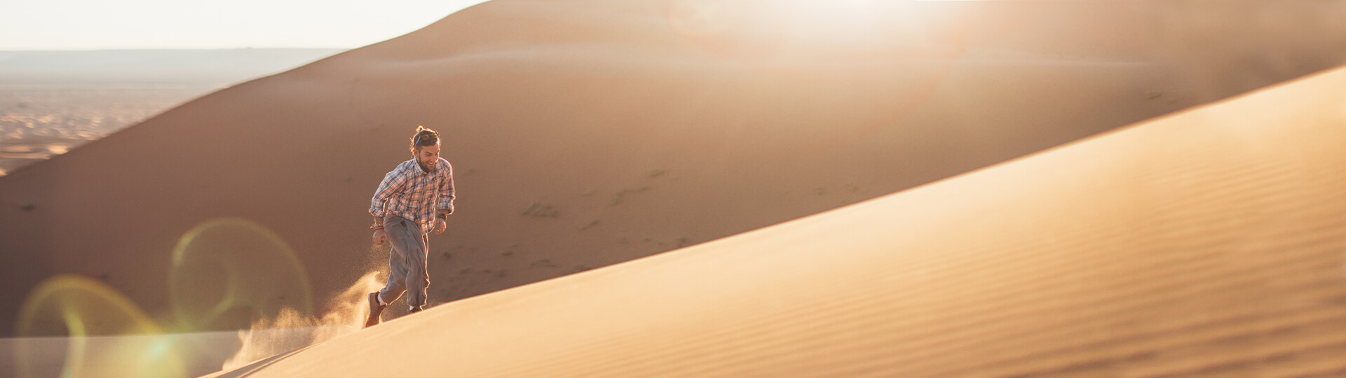 Excited looking man running up the desert dunes in the middle east.