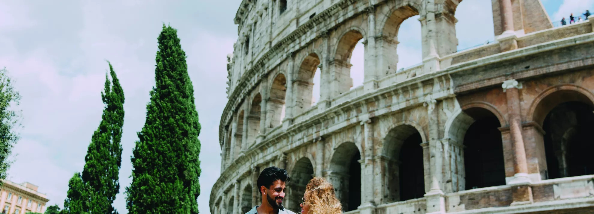 A romantic couple standing in front of the Colosseum 