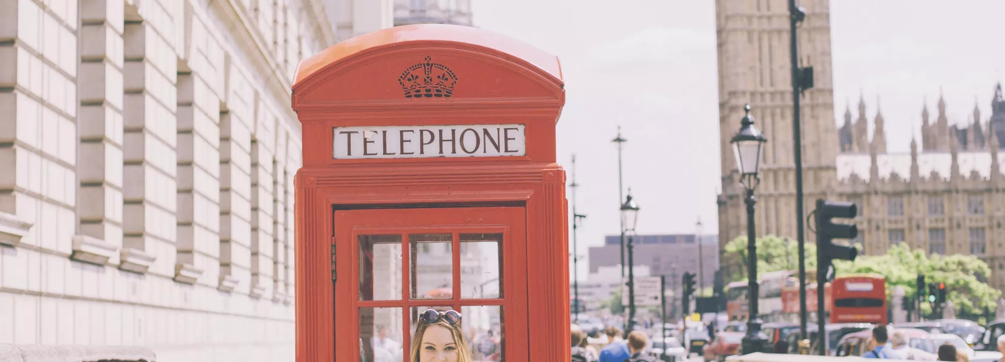 A woman standing in front of a red telephone box, with Big Ben in the background