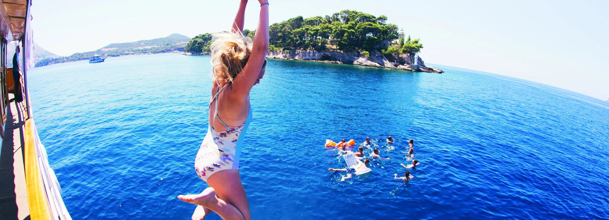 Woman jumping off a boat into the sea in Croatia