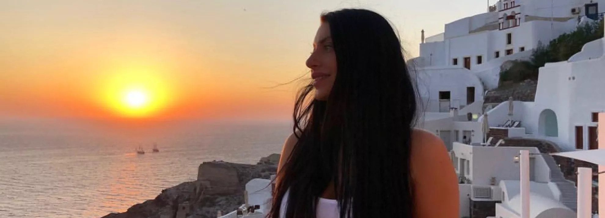 Woman standing in front of a greek sunset
