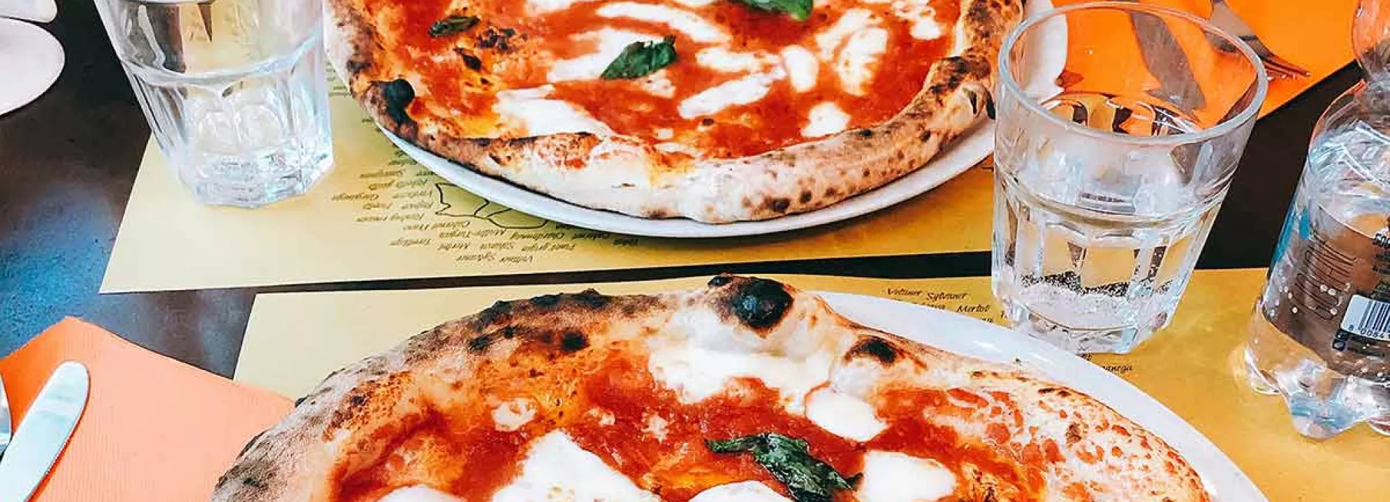 Two margarita pizzas on a table at a restaurant 