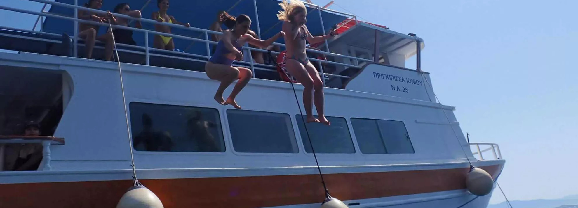 Two women jumping off a boat into the sea