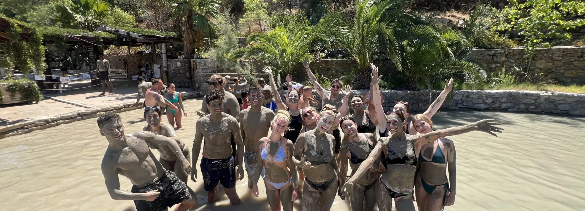 A group of topdeckers standing in a river with mud on them