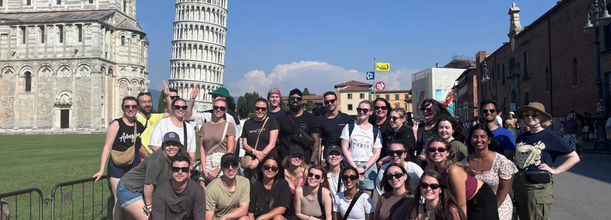 A group picture of topdeckers in front of the leaning tower of Pisa
