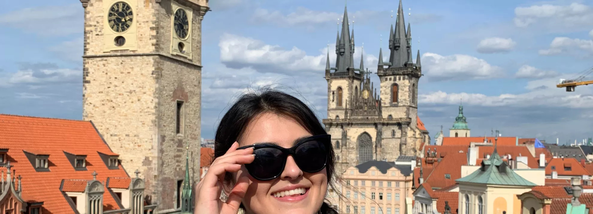 A woman wearing sunglasses with the city behind her