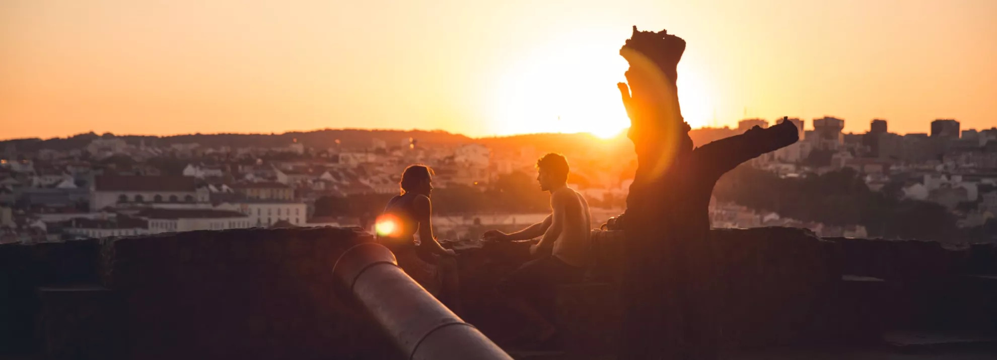 A couple sitting on a roof at sunset