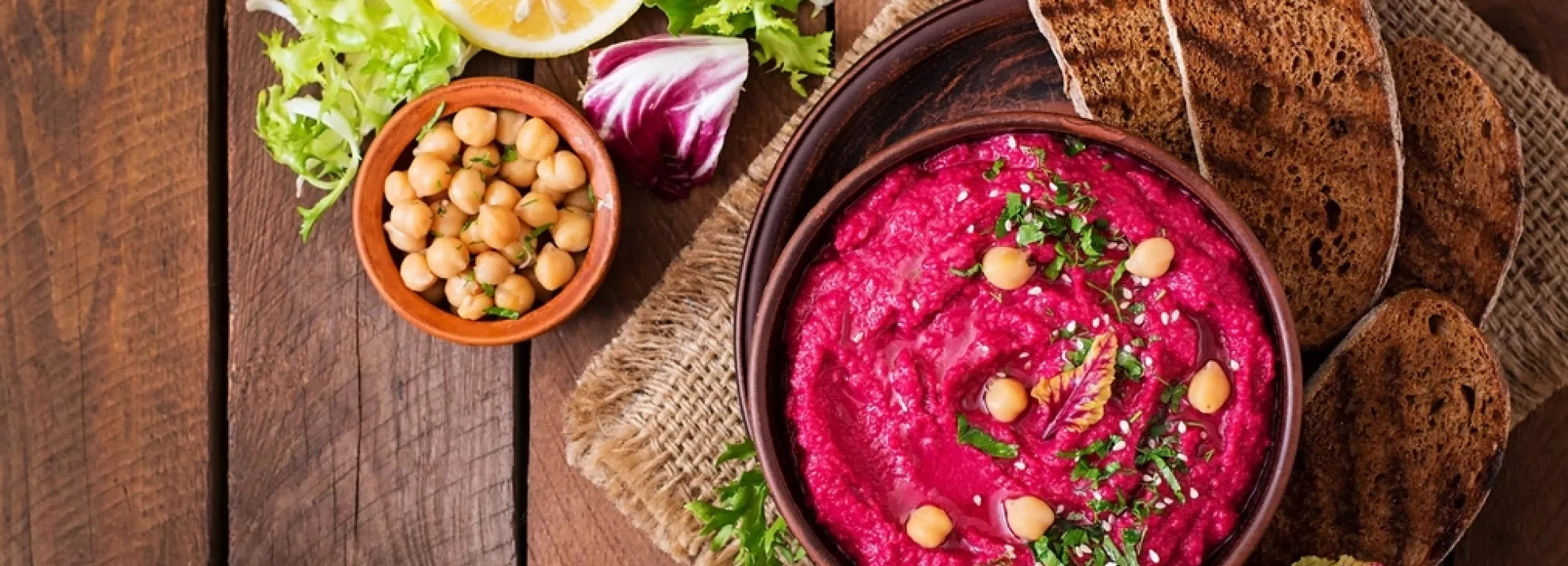 A table with pink hummus and chickpeas in a small bowl on the side