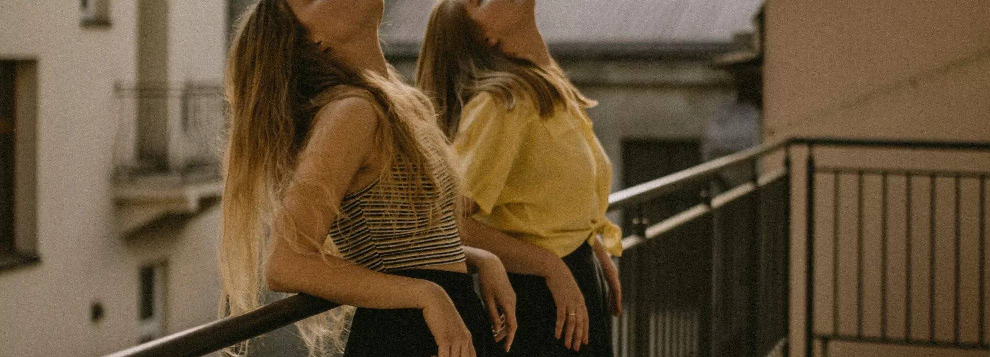 Two women leaning on a railing, with their heads up