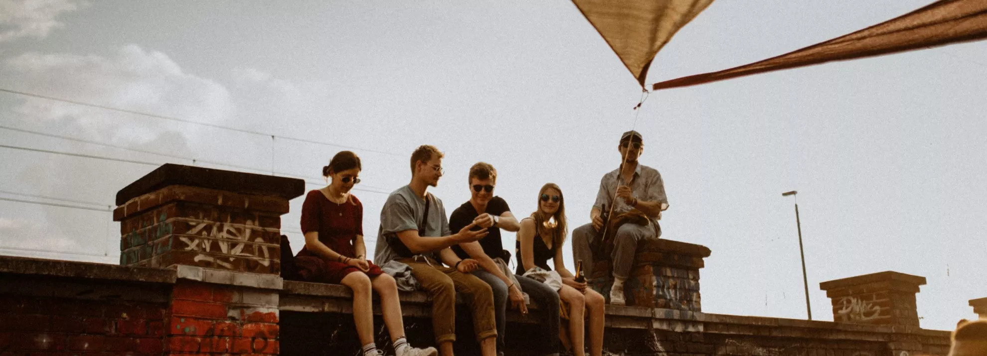 A group of people sitting on top of a wall, with a crowd below them