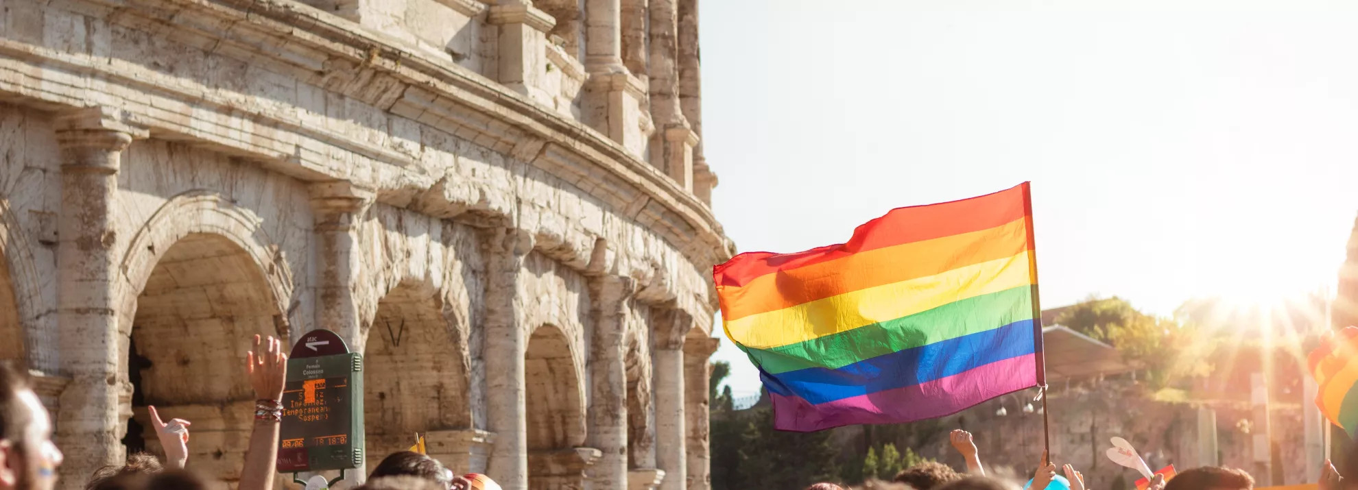 A pride march, in the background is the colosseum
