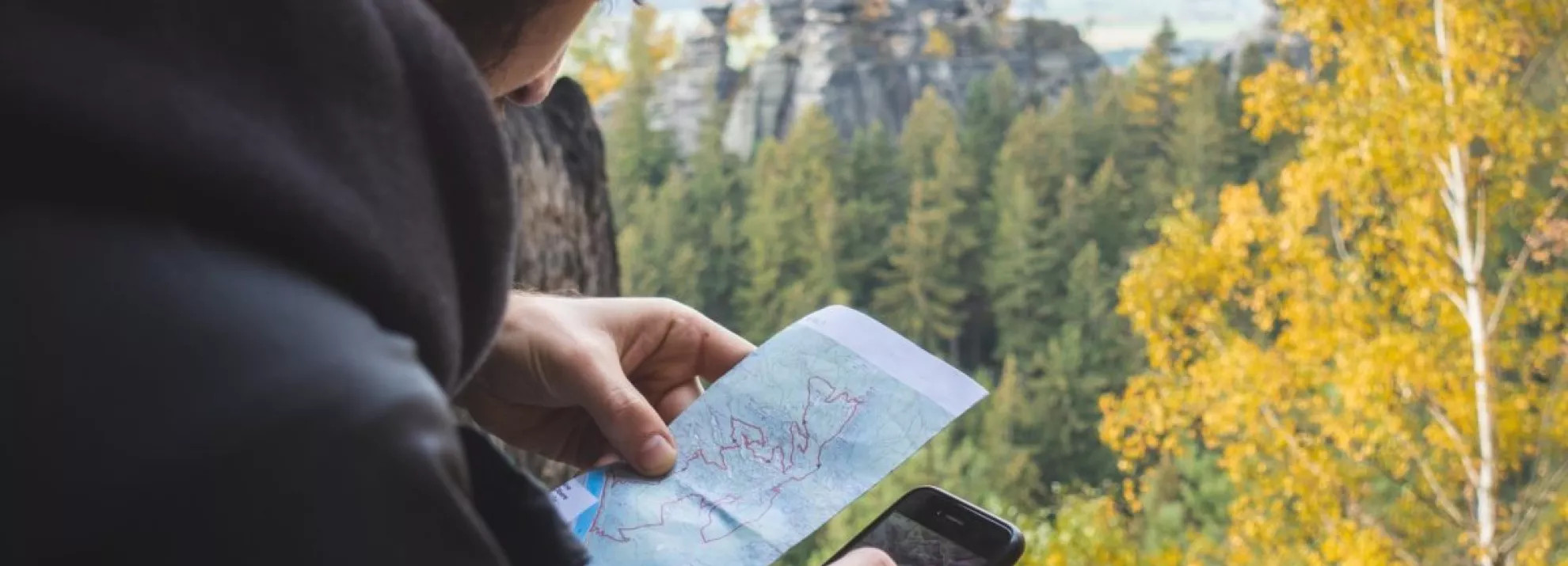 Man using a map and his phone to navigate a forest