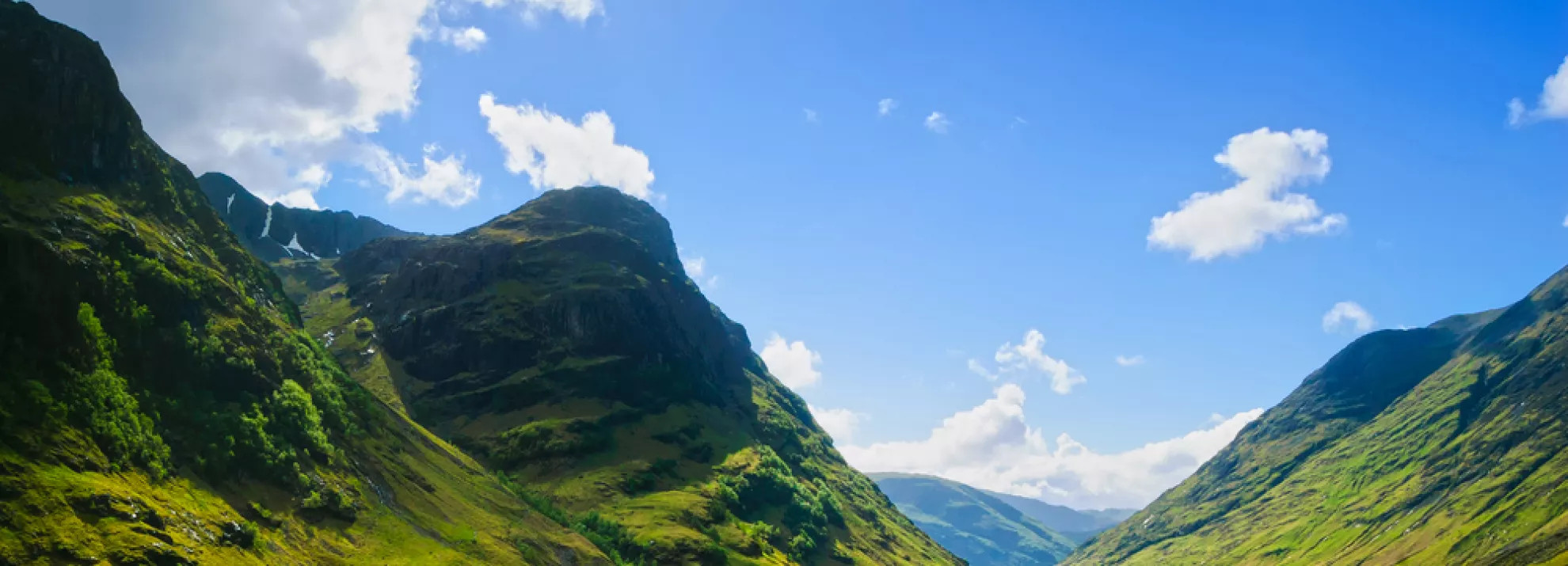 Green Scottish mountains and a bright blue sky