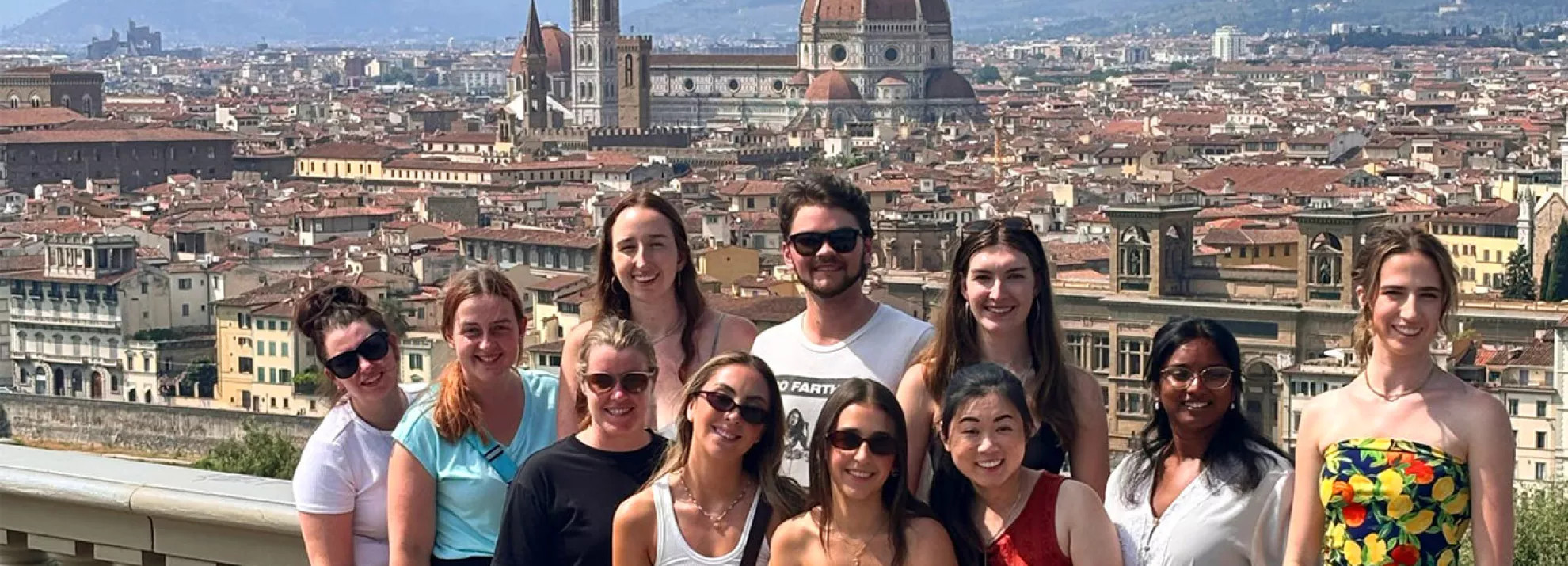 Group of people standing together with view of Florence behind them.