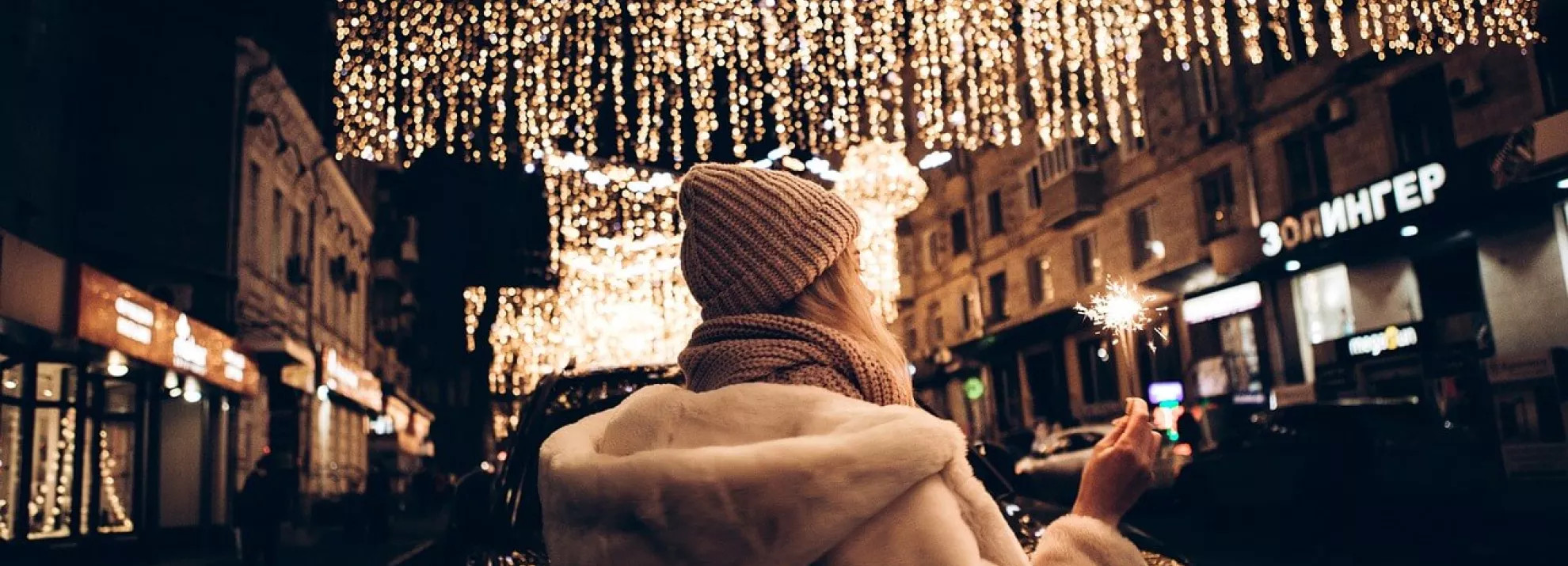 A woman holding a sparkler under fairy lights
