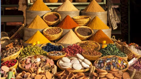 Display of spices and other Moroccan food items piled in woven baskets.