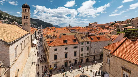 Old Town of Dubrovnik with stone buildings with towers and orange tiled roofs.