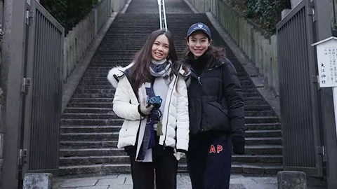 Two people standing together smiling at the bottom of an outdoor staircase.