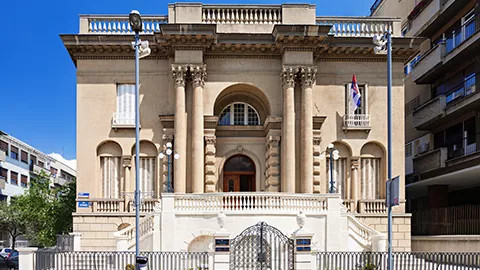 Large cream coloured building with four pillars side the front door.