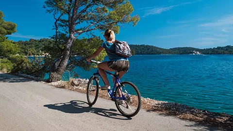 Person cycling on a path next to the ocean.