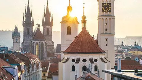Taller buildings in Prague, Czech Republic with the sun rising in behind.