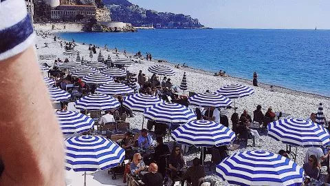Blue and white umbrellas lined along the beach front in Nice, France.