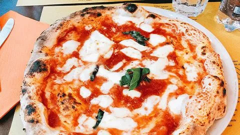 Wood fire margarita pizza with fresh basil sitting on a table.