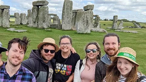 Group of people posing in front of Stonehenge.