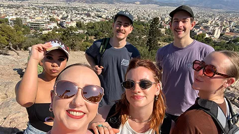 People taking a selfie together near the Acropolis with the city of Athens behind them.