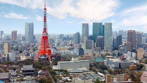 The orange Tokyo Tower stands tall among other buildings in the city.