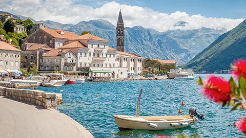 Small boat floating on the water with a European town in the background.