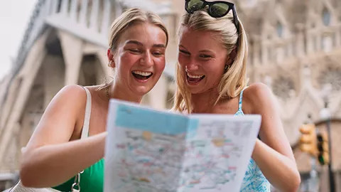 Two people smiling while pointing at a map while standing outside the Sagrada Família.