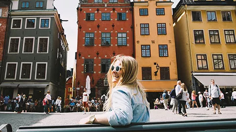 Person wearing sunglasses in front of various coloured buildings.