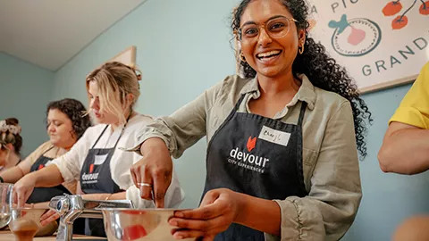 Person smiling while mixing ingredients in a bowl at a pasta making class.
