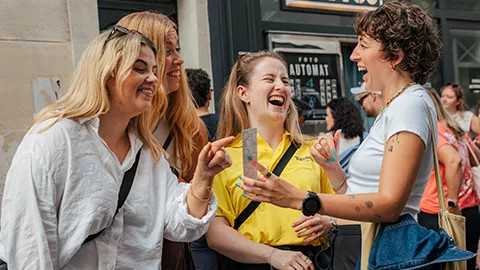 People laughing together at a photo strip printed from a photobooth.