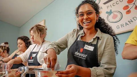 Person smiling while mixing ingredients in a bowl at a pasta making class.