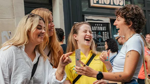 People laughing together at a photo strip printed from a photobooth.