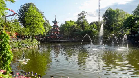 Man made pond with water feature in lush park.