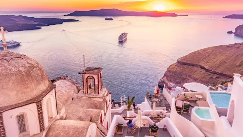 View of white rooftops in Santorini with sunsetting on the horizon.