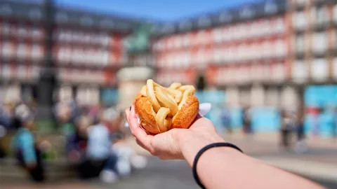 Hand holding out a Bocadillo de Calamares in Madrid, Spain.