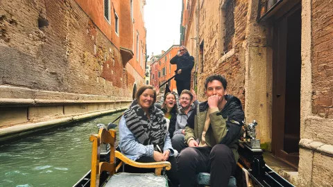 People on board a gondola boat in a Venice canal.