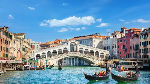 Gondola boats floating on the Grand Canal in front of the Rialto Bridge in Venice.