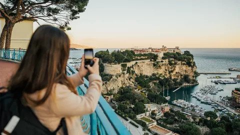 Girl takes a photo on her iPhone of Monaco in the French Riviera.