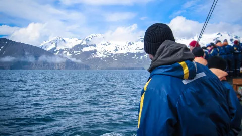  People standing on side of whale watching boat.