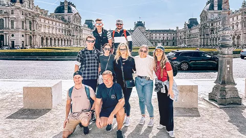 Group of people taking a photo in front of The Louvre